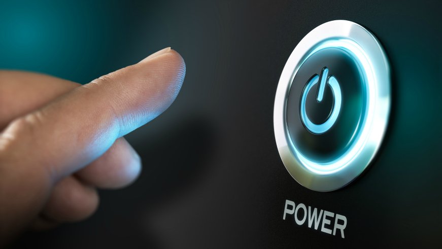 A close-up of a finger about to press a glowing power button on a black device. The button is surrounded by a blue light, and the word *POWER* is visible below it.